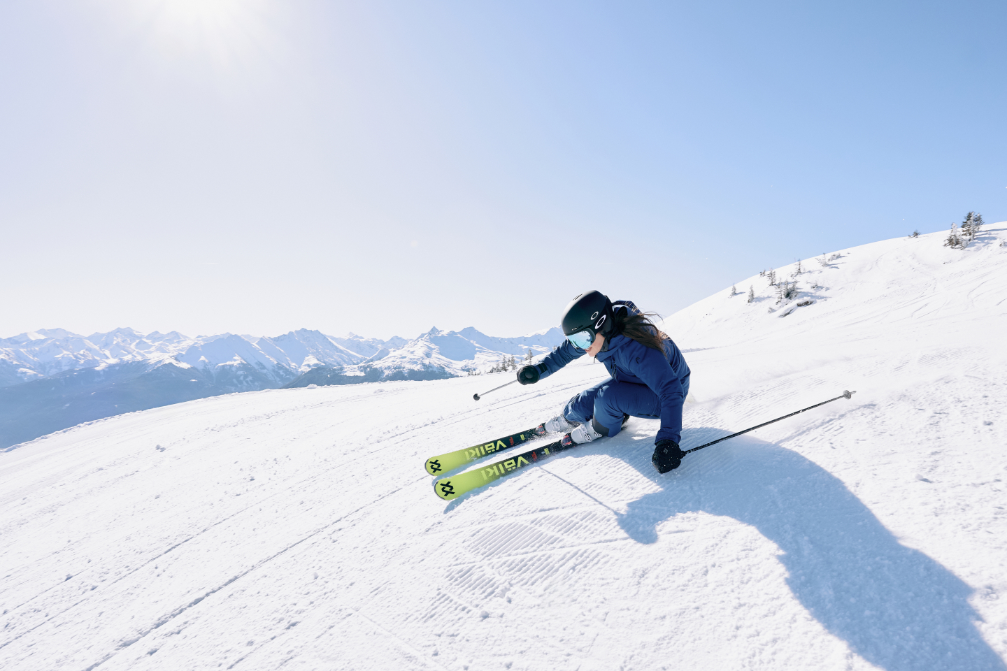 Woman skiing downhill on a sunny day in the mountains; winter sports adventure.