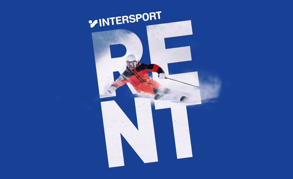 Ein Skifahrer in roter Ausrüstung fährt eine Piste hinunter, vorbei an großen weißen Buchstaben, die auf blauem Hintergrund das Wort „RENT“ bilden, und vermittelt dabei Action und Sportlichkeit.