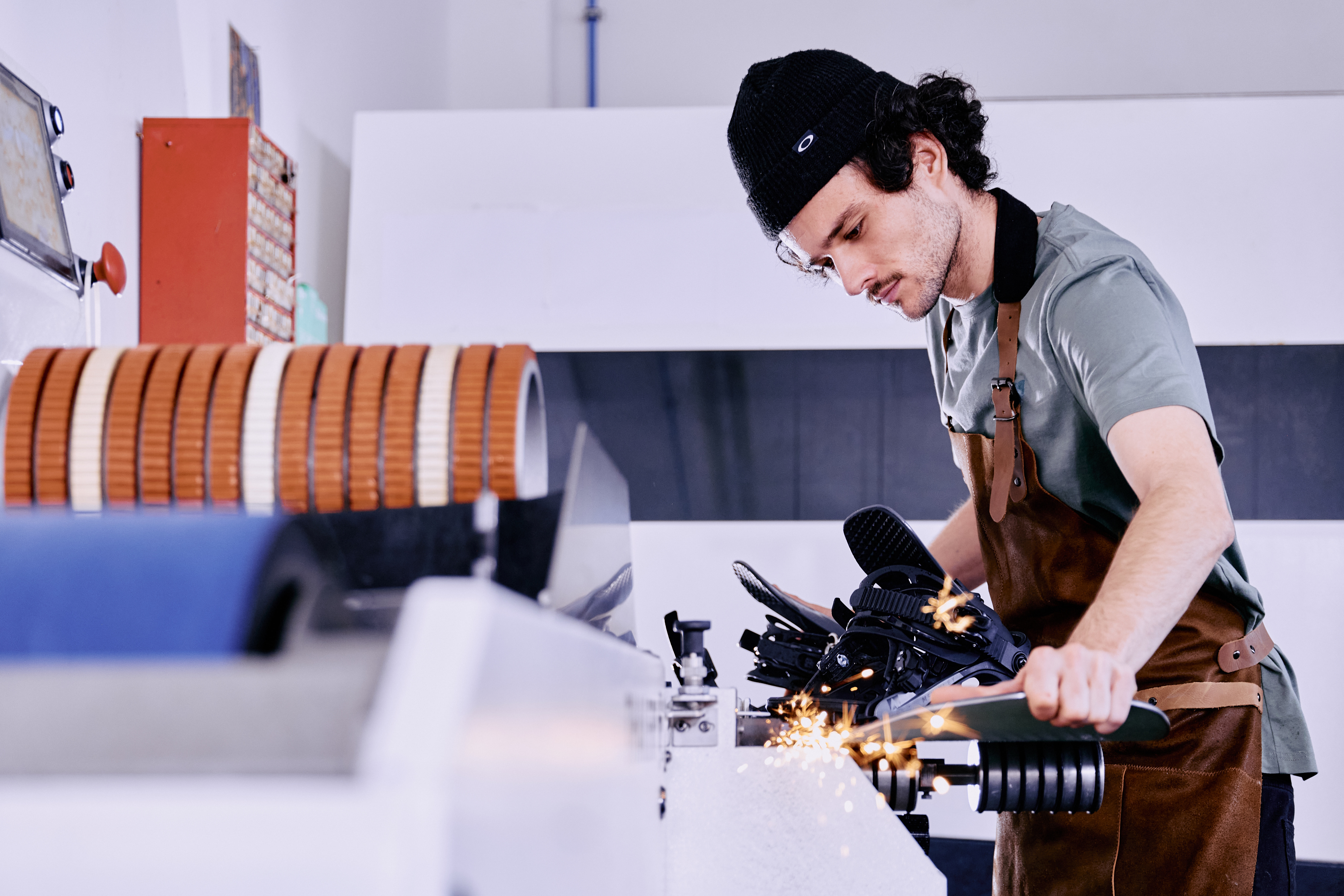 Ein konzentrierter Arbeiter in einer Schürze bedient eine Maschine und justiert präzise ein Metallteil. Die Szene vermittelt Konzentration und handwerkliches Können in der Industrie.